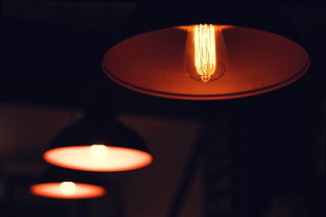 Three vintage lamps hanging in a dark room.