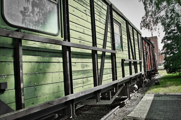 Historic railway carriage with peeling green paint on the outer walls made of wooden boards.