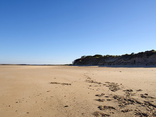 Breiter Sandstrand in der Normandie unter blauem Himmel