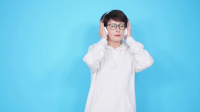 Love for music concept. Mature Woman Streams Music in Headphones on a blue background