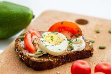 Sandwich with tomato, egg and seeds on whole grain bread. The concept of healthy eating.