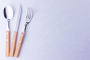 Set of cutlery: knife, fork, spoon on white background. Table setting. Concept of cutlery with wooden handles - laconic minimalistic design. Top view