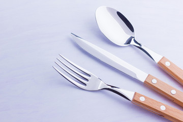 Set of cutlery: knife, fork, spoon on white background. Table setting. Concept of cutlery with wooden handles - laconic minimalistic design. Top view