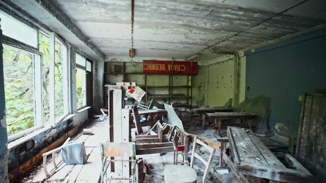 View interior inside radioactive dirty old working room in abandoned building with soviet union political slogans. Summer dark tour to Chernobyl and Prypiat city.