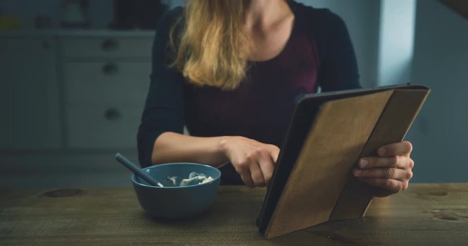 Woman having breakfast and using tablet computer