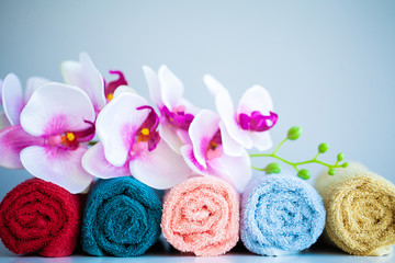 Obraz na płótnie Canvas Colored towels and orchid on white table with copy space on bath room background.
