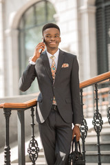 handsome young african man in a suit talking on the phone