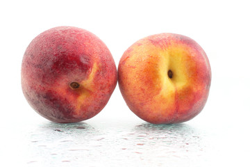 two ripe peaches in the water droplets on white background