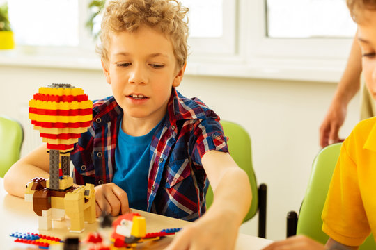 Cute blonde boy taking some constructor set details