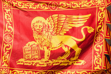 Old Venice Republic Flag with Saint Mark Lion and motto 'Pax tibi Marce, evangelista meus' (Peace be with thee, O Mark, my evangelist) fluttering in the wind as background