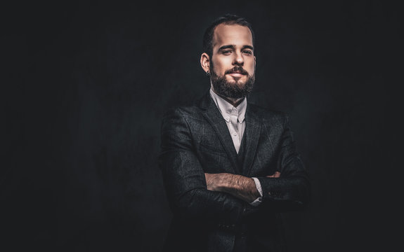 Portrait of handsome bearded stylish male, wearing an elegant suit on a dark background.