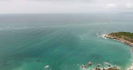 Aerial shot of a beautiful seaside landscape of an Adriatic sea in the summer. Quadcopter flies over the seacoast covered with green forest and flies to the turquoise sea 
