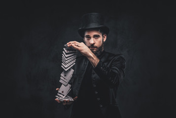 Magician showing trick with playing cards on a dark background.