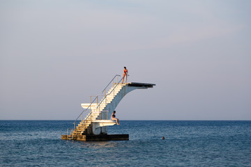 Aerial view of young womans on a sea diving board. Elli beach, the main beach of Rhodes town....