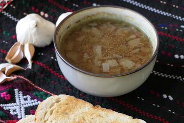 Warm Homemade Lentils Soup with Garlic and Bread Slices on a Dark Background