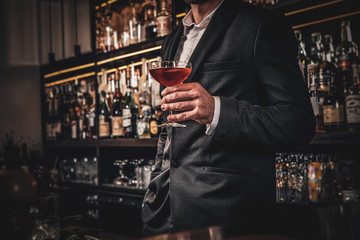 Elegant handsome man in classic suit is consuming alcohol at the nice bar.