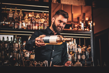 Elegant happy bar owner is making special drink for his customers at his own bar.