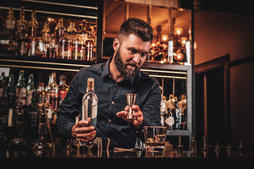 Elegant happy bar owner is making special drink for his customers at his own bar.