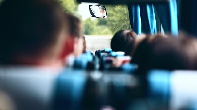 Tourism, people and transport concept. Back view of crowd of tourists inside the travel bus driving to his destination. Exciting roadtrip.