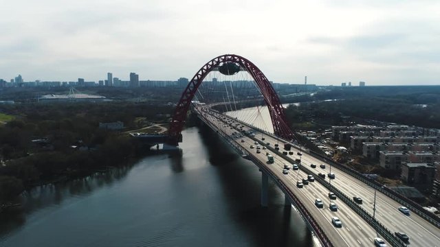 Aerial view of picturesque bridge over the Moscow-river and road traffic, the prospectus of Marshal Zhukov with moving cars against cloudy sky. Scene. Moscow skyline in summer