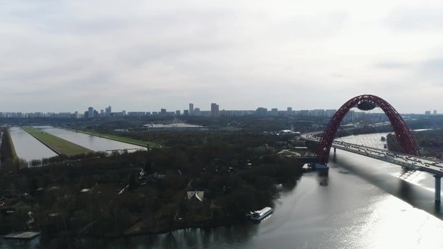 Aerial view of picturesque bridge over the Moscow-river and road traffic, the prospectus of Marshal Zhukov with moving cars against cloudy sky. Scene. Moscow skyline in summer