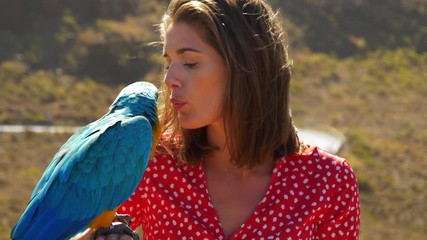 Pretty Model Blows a Kiss to Her Pet Macaw Parrot on a Sunny Day - Powered by Adobe