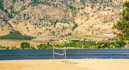 Sand beach with installed valleyball net for the game. Okanagan lake view with mountain background