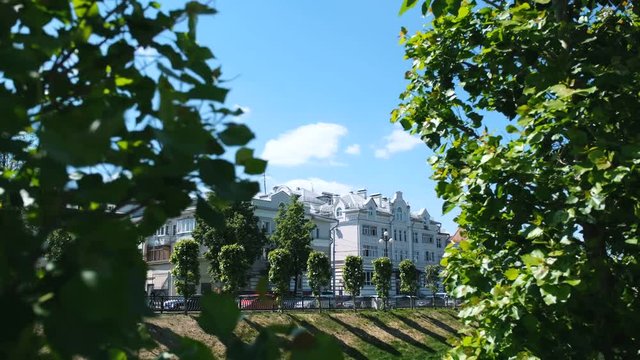 Close-up view of green leaves with Chernoyarovsky Passage, on the background in summer day. Stock footage. Kazan city, Tatarstan republic, Kremlevskaya street