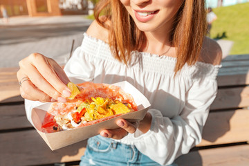 Happy asian girl eating taco outside. Mexican fastfood cuisine. Tasty and spicy snack in park