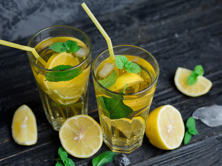 Fototapeta premium Two glasses of Mojito or lemonade on a dark table. Drink with lemon and mint