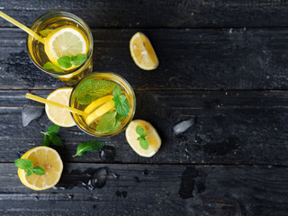 Two glasses of Mojito or lemonade on a dark table. Drink with lemon and mint