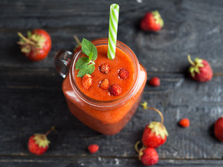 A can of red strawberry smoothie on a wooden table. Summer delicious smoothie
