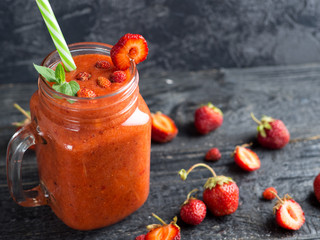 A can of red strawberry smoothie on a wooden table. Summer delicious smoothie