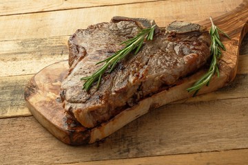Marbled beef steak on rosemary board, on wooden background, restaurant menu, gastronomy, delicious food