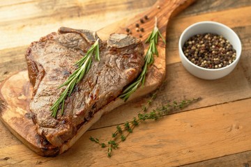 Marbled beef steak on a board with rosemary pepper, spices, on a wooden background, restaurant menu, gastronomy, tasty food
