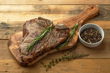 Marbled beef steak on a board with rosemary pepper, spices, on a wooden background, restaurant menu, gastronomy, tasty food