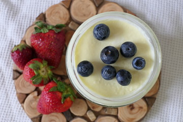 Homemade Yoghurt in a Jar with Fresh Strawberries and Blueberries on a Wooden Background