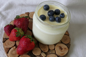 Homemade Yoghurt in a Jar with Fresh Strawberries and Blueberries on a Wooden Background