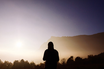 Silhouette of a man against the backdrop of misty mountains. Female silhouette on the background of misty mountains.