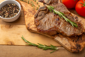 Marbled beef steak on a board with rosemary pepper, spices, and fresh vegetables on a wooden background, restaurant menu, gastronomy, tasty food. Horizontal photo, banner