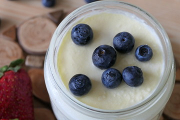 Homemade Yoghurt in a Jar with Fresh Strawberries and Blueberries on a Wooden Background