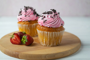 Freshly baked cupcakes with strawberry frosting and chocolate sprinkles