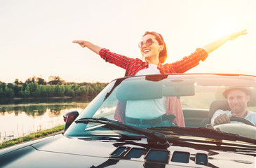 Happy couple in love go by cabriolet car in sunset time