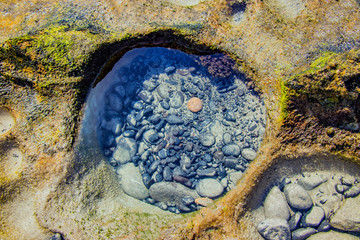 Small black stones in salt water of Atlantic ocean in cliff on the beach