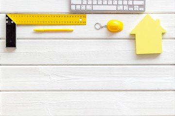 ruler, keyboard, house figure, tools for architect work on white wooden desk background top view copyspace