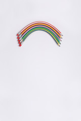 Lápices flexibles de diferentes colores formando un arcoiris sobre fondo vertical blanco