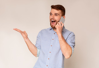 Handsome guy happy to hear good news talking on phone