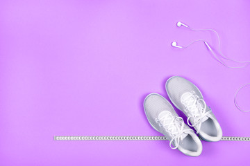 White sneakers with measuring tape and earphones (headphones)  
on blue background. 
