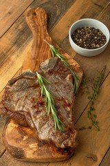 Marbled beef steak on a board with rosemary pepper, spices, on a wooden background, restaurant menu, gastronomy, tasty food