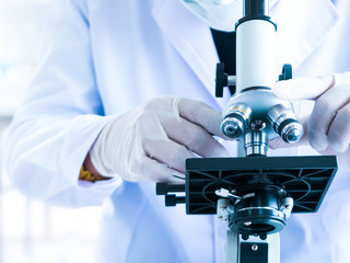 Scientist use microscope for experiment research test about biotechnology close up hand in laboratory